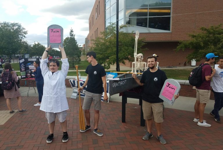 members eagerly recruiting at the involvement fair with the graveyacht canoe and a skeleton sitting int it 